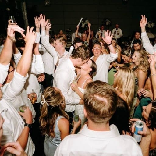 Wedding guests with their arms raised on the dance floor, the kind of candid moment guests capture and upload